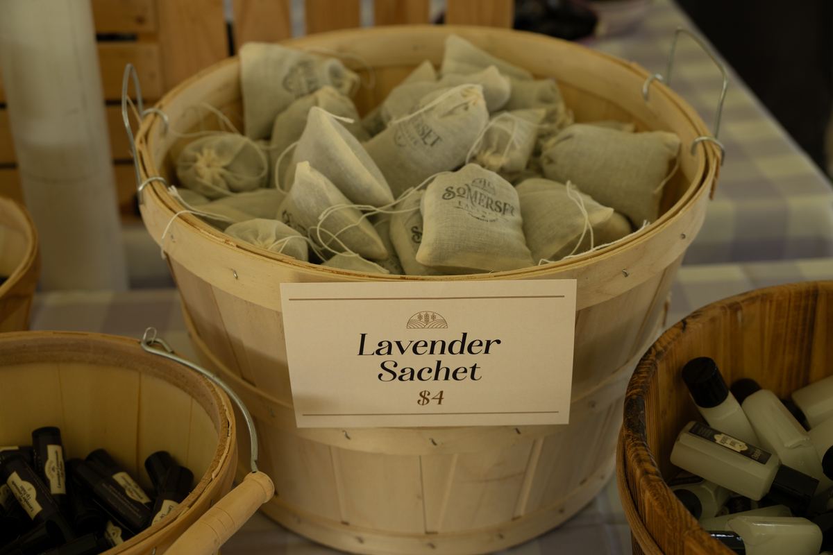 Somerset Lavender sachets piled in a wooden bushel basket with a hand-lettered price card